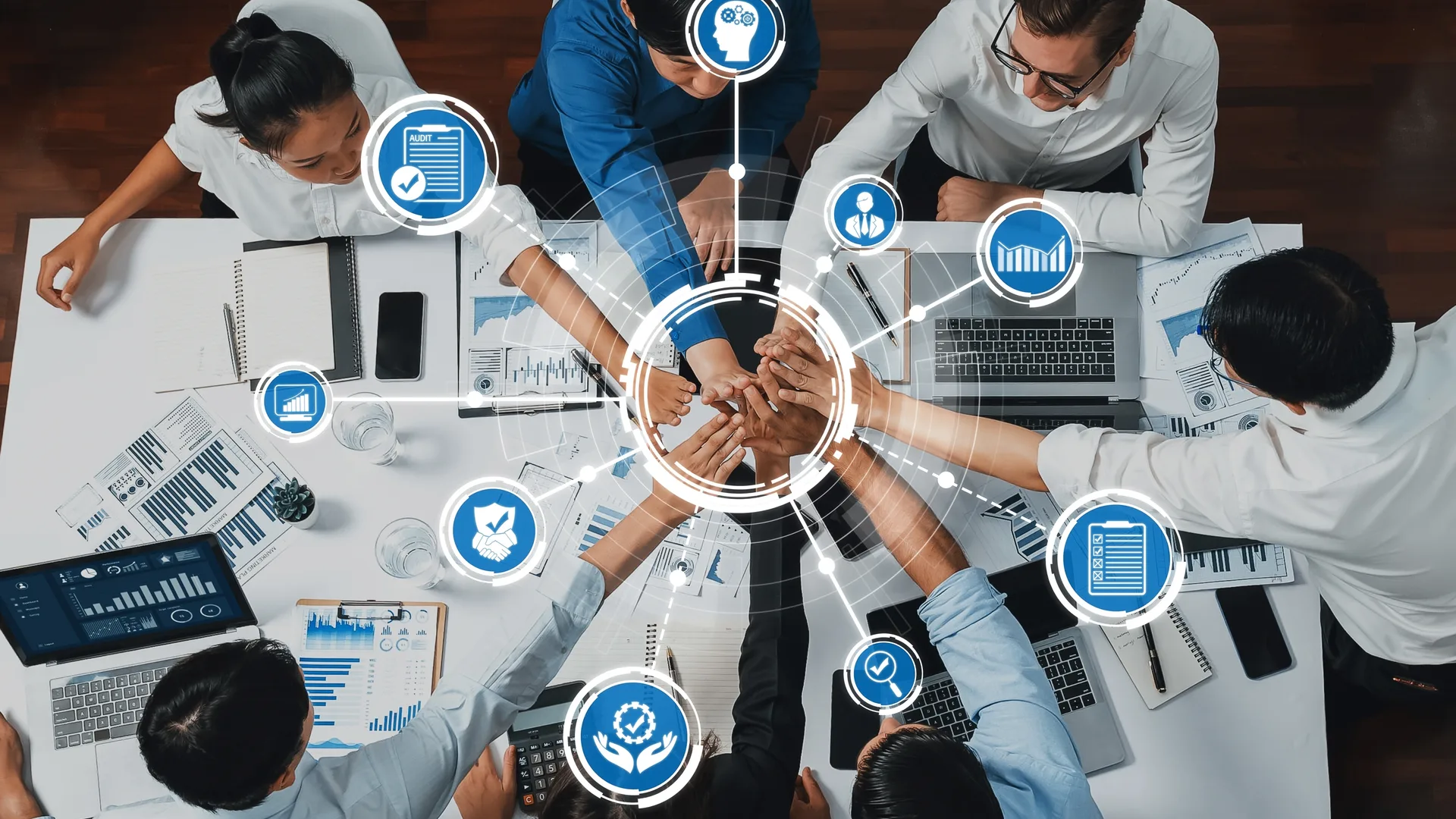 A team joining hands over a shared workspace